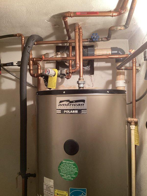 Responded to service call for intermittent hot water issues on approximately 10-year-old residential water heating system. Upon arrival, performed diagnostic inspection of American Standard Polaris heating unit and associated plumbing components. Evaluated copper piping network, pressure gauges, shut-off valves, and control panel indicators. Inspected unit for potential leaks, verified drain pan condition, and examined all visible connections and fittings. Documented system configuration including Energy Star certified unit with multiple safety labels and warning indicators. Assessed control panel operation, temperature settings, and indicator lights to determine intermittent performance patterns reported by occupant regarding insufficient hot water supply and duration.