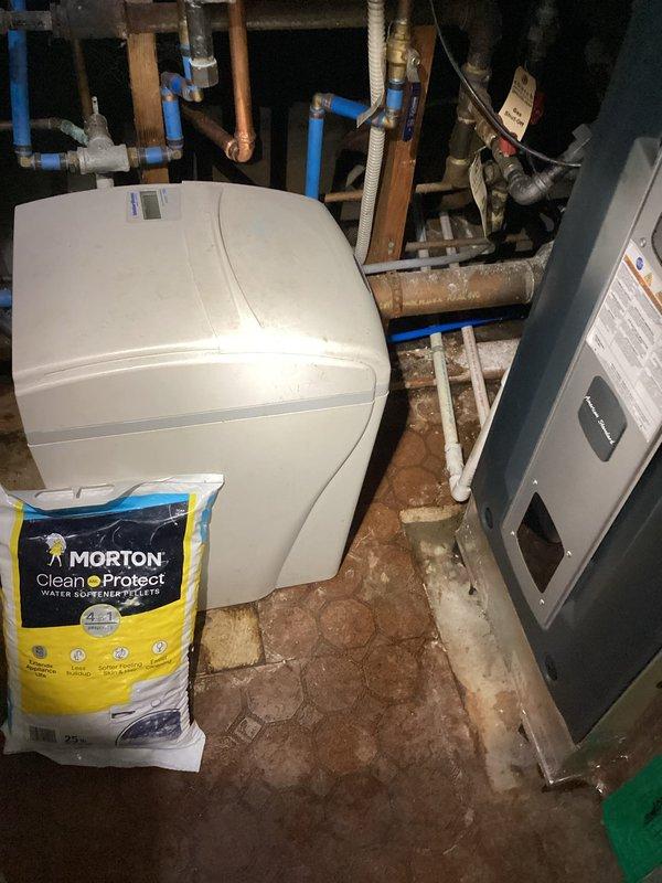 Responded to service call for standing water in crawlspace with suspected HVAC or plumbing leak. Upon inspection, examined furnace area adjacent to crawlspace and surrounding utility equipment including water softener system and associated plumbing connections. Photographed installation to document current conditions of blue PEX piping, copper lines, and drainage components in utility area. Determined leak source was not related to HVAC system, as 4-year-old furnace showed no signs of condensate line failure or refrigerant leakage.