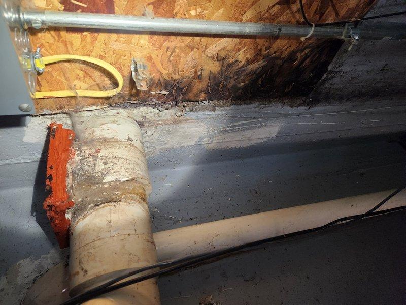 Responded to service call regarding sewer gas odor emanating from drainage system. Upon inspection of the utility area, identified a floor drain assembly with an improperly functioning or damaged trap primer device that was allowing sewer gases to escape into the building. The device in question appeared to be connected to the main drain line where it exits the building foundation. Documented existing conditions with photographs showing the drain configuration, PVC piping layout, and the suspected gas leak source. Advised customer on options for remediation, including potential replacement of the trap primer assembly or elimination of the device if not required by current plumbing code. Recommended follow-up evaluation to determine the most appropriate solution based on local code requirements and building usage.
