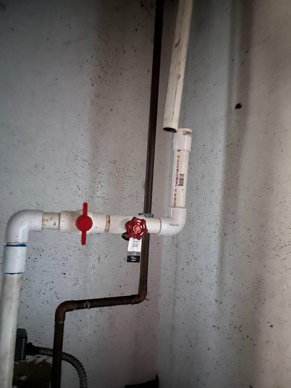 Responded to a broken fitting on the sprinkler system piping in the basement. Upon arrival, confirmed the water supply was already shut off and no active leaking or property damage was present. Inspected the PVC sprinkler line assembly, including the gate valves, connections, and vertical pipe configuration. Documented the existing plumbing installation showing the white PVC piping system with red valve handles and the connection points where the fitting failure occurred. Provided assessment and recommendations for repair of the damaged fitting to restore the sprinkler system to proper working condition.
