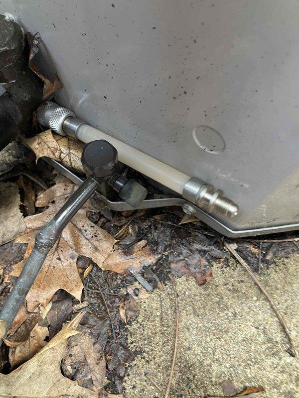Responded to unit 111 for air conditioning evaluation and documented frozen evaporator coil condition causing water drainage issues into the unit below. Photographed damaged HVAC equipment panel and exterior condensate drain line area with accumulated debris, scheduling return visit to address frozen coil repair and restore proper system operation.