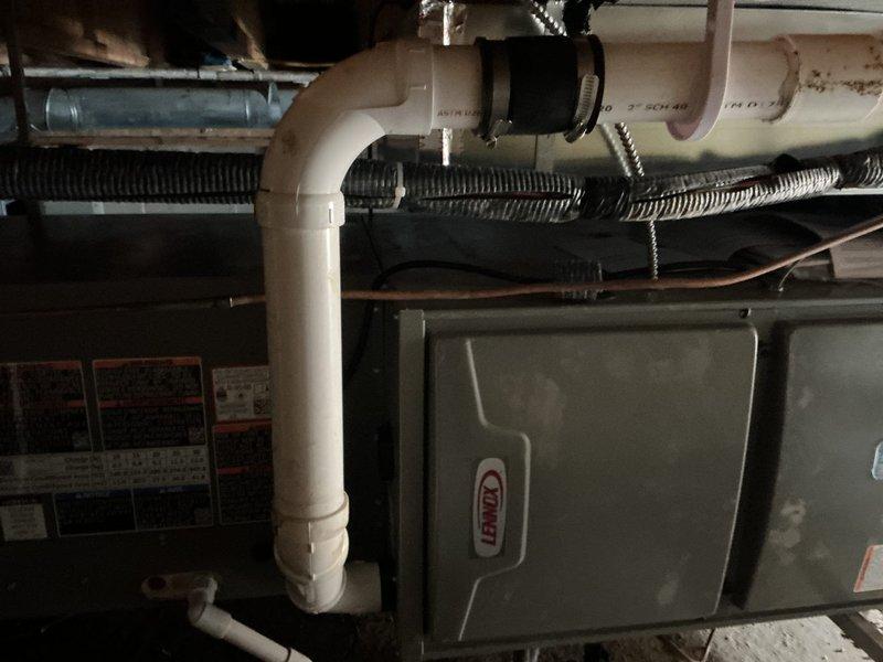 Completed installation of Lennox ML17KC2-036-230 air conditioning condenser unit and CK40HT-30B-71 evaporator coil. Established proper condensate drainage system utilizing white PVC piping with secure mounting and installed condensate pump on concrete floor to handle moisture removal from the new cooling system. Verified all electrical connections, refrigerant lines, and ductwork integration with existing Lennox furnace to ensure proper system operation and airflow throughout the residence.