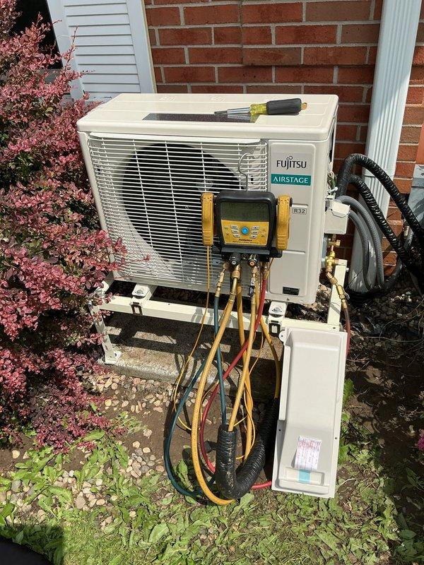 Completed installation of Fujitsu Airstage mini-split heat pump system at residential property. Mounted AOLH12KNAS1 outdoor condensing unit on metal bracket against brick exterior wall with proper elevation and drainage clearance. Installed ASLH12KNAS indoor air handler unit. Replaced existing line set with new refrigerant lines, properly insulated and routed along exterior wall. Established refrigerant connections between indoor and outdoor units. Evacuated system using vacuum pump to remove moisture and non-condensables from refrigerant lines. Charged system with appropriate refrigerant type and quantity per manufacturer specifications. Connected electrical supply and control wiring between units. Tested system operation in both heating and cooling modes to verify proper performance. Confirmed adequate airflow, temperature differential, and refrigerant pressures using digital manifold gauges. System operating within normal parameters upon completion.