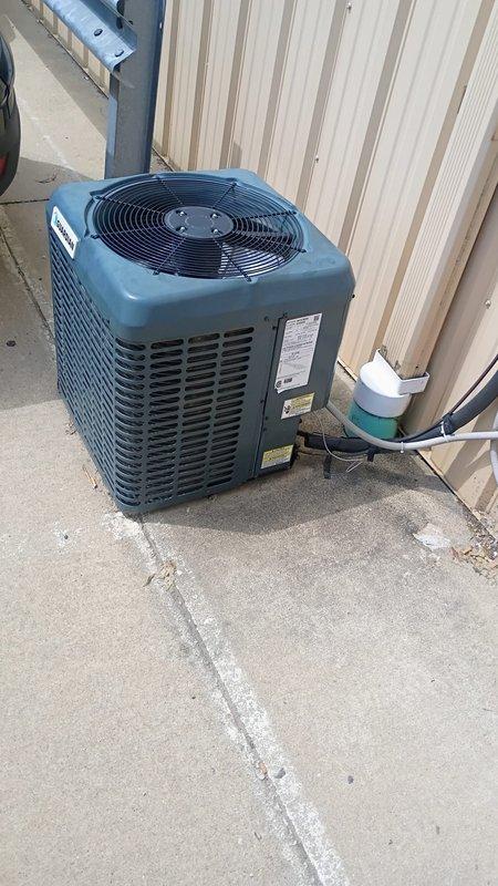 Responded to service call for non-operational HVAC system on east side of building and malfunctioning thermostat. Inspected outdoor condensing unit with top-mounted fan and verified unit specifications. Evaluated indoor air handler located in mechanical room alongside water heater and ductwork system. Diagnosed thermostat communication failure preventing proper system operation. Restored cooling functionality to affected zone and verified adequate airflow through supply vents with no ice buildup present on evaporator coil.