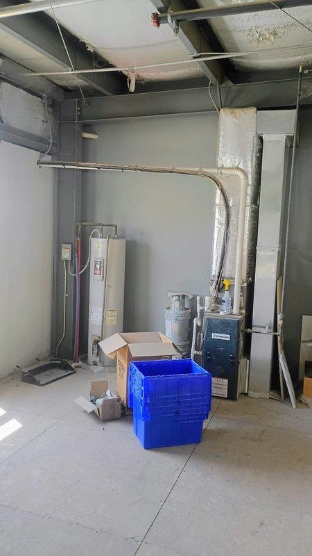 Responded to service call for non-operational HVAC system on east side of building and malfunctioning thermostat. Inspected outdoor condensing unit with top-mounted fan and verified unit specifications. Evaluated indoor air handler located in mechanical room alongside water heater and ductwork system. Diagnosed thermostat communication failure preventing proper system operation. Restored cooling functionality to affected zone and verified adequate airflow through supply vents with no ice buildup present on evaporator coil.