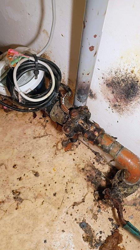 # Plumbing Service - Broken/Burst Pipes - CH

Responded to emergency service call for actively leaking copper pipe causing property damage in utility room. Upon arrival, confirmed water supply had been shut off by customer to prevent further damage. Conducted thorough assessment of affected area, revealing severely corroded copper piping with heavy oxidation and deterioration at joints and connections. The corrosion presented as dark greenish-black buildup with significant decomposition of pipe material, indicating long-term exposure to moisture and aging infrastructure. 

Documented extensive property damage including water staining on walls, floor contamination, and accumulated debris throughout the utility space. Photographed corroded pipe sections, connection points, and surrounding area to provide visual record of conditions. The affected copper line showed advanced stage corrosion requiring immediate attention to prevent recurrence of leak and potential system failure. Assessed s
