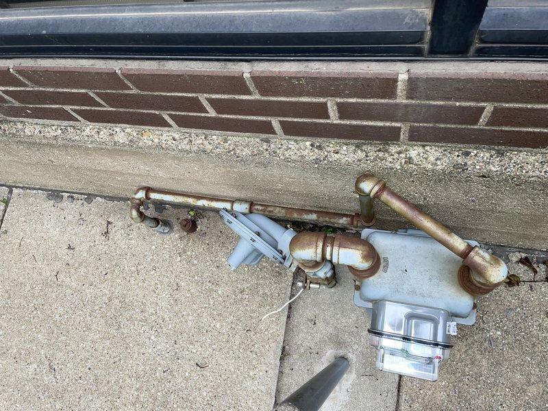 Responded to commercial gas line issue in century-old building that had been affecting a specific area for two weeks. Conducted comprehensive pressure test on central heating system, inspecting aged copper piping with significant oxidation and patina, exterior plumbing assembly with brass fittings, and PVC components including meter housing. Evaluated structural areas including crawl space where PVC lines run through weathered wooden joists and alongside aged concrete surfaces, documenting condition of all gas line connections, joints, and related infrastructure to identify source of ongoing issue.