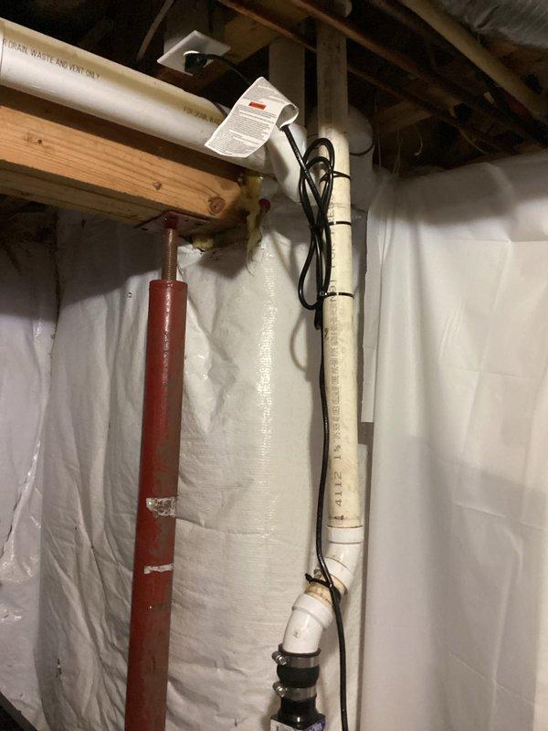 Responded to emergency flooding situation in basement caused by failed sump pump system. Upon arrival, found approximately 1 inch of standing water covering 15-foot radius around sump pit. Assessed existing sump pump installation, documented wet concrete floor conditions and active water infiltration around corroded metal pit cover. Photographed complete system including vertical PVC discharge piping with mounting straps, electrical connections, and moisture barrier installation on surrounding walls.