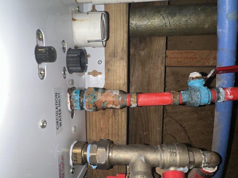 Responded to callback for water leak concerns on hot and cold supply lines following previous water heater repair. Upon inspection, discovered significant corrosion and oxidation on copper supply piping near water heater connections, with heavy turquoise-green patina indicating long-term deterioration at pipe joints and fittings. Documented existing conditions with photos showing corroded copper lines, brass valve assembly, and control components. Assessed that current leaking was due to pre-existing pipe corrosion rather than recent repair work, as deterioration patterns indicated prolonged exposure to moisture and mineral deposits. Advised customer of findings and recommended replacement of corroded supply lines to prevent future leaks.