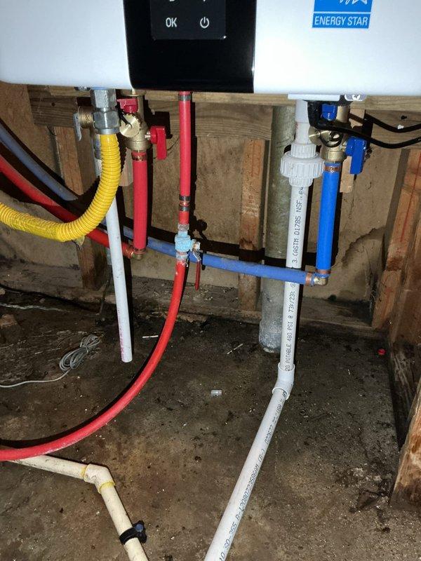 Replaced existing Navien tankless water heater with new NPE-180A2 model in unfinished basement utility area. Obtained necessary permit prior to installation and completed all required plumbing connections including hot and cold water PEX supply lines with ball valve shutoffs, gas line integration via flexible corrugated tubing, and proper venting through white PVC exhaust and intake pipes. Verified electrical connections to control panel, tested unit operation to confirm "OK" status on display, and ensured all connections were secure and leak-free.