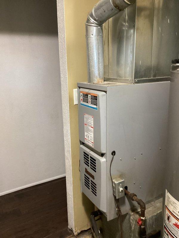 Responded to service call for water intrusion through furnace exhaust system during rain events. Performed comprehensive inspection of furnace unit and exhaust venting system in utility room. Examined furnace exterior, ductwork connections, and exhaust termination components for signs of moisture infiltration. Documented evidence of water damage and discoloration on affected surfaces. Inspected metallic exhaust piping, joints, and seals for potential entry points. Verified furnace operational status and confirmed unit functioning normally despite moisture issue. Assessed roof penetration point and exhaust vent termination as probable source of water entry. Captured photographic documentation of furnace installation and water damage evidence for records. Recommended roof-level inspection and potential resealing of exhaust vent flashing and termination cap to prevent future water intrusion during precipitation events.
