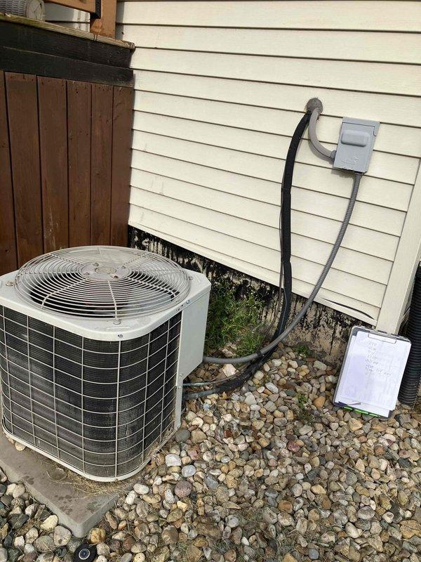 Conducted comprehensive HVAC system evaluation for complete replacement estimate at residential property. Assessed existing Bryant split system configuration consisting of outdoor condensing unit positioned on concrete pad with gravel drainage bed and indoor air handler/furnace combination located in basement mechanical room. Documented current equipment condition, noting significant condensation accumulation on evaporator coil unit indicating potential efficiency concerns, moisture staining at building foundation near outdoor unit suggesting drainage issues, and overall system age and performance characteristics. Evaluated electrical disconnect, refrigerant line routing, PVC condensate drainage, and existing ductwork connections to determine replacement specifications and compatibility requirements for new high-efficiency system installation.