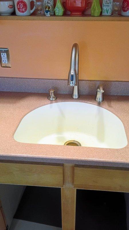 Completed kitchen faucet replacement in 1950s-era home with customer-supplied fixture. Removed existing faucet assembly, installed new brushed stainless steel pull-down model with dual handles and verified all supply line connections beneath sink for proper operation. Tested hot and cold water flow, checked P-trap and drainage system for leaks, and confirmed no issues with existing plumbing infrastructure.