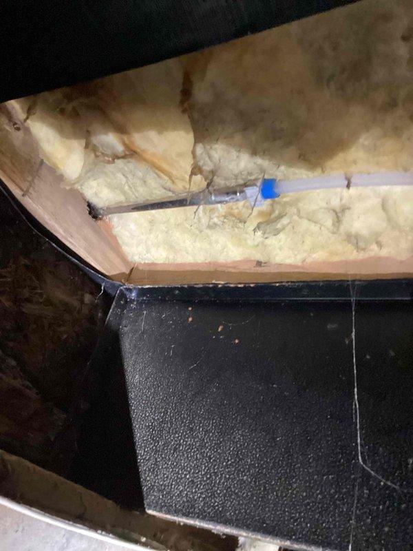 Responded to call for exterior wall leak occurring only when front yard hose spigot was operated. Conducted diagnostic inspection of outdoor spigot assembly and traced water intrusion path. Investigation revealed leak originating from failed connection or damaged pipe behind exterior wall penetration at spigot mounting location. Inspected attic space above affected area to assess potential water damage to insulation and structural components. Documented existing water staining on fiberglass insulation between roof rafters, indicating previous or ongoing moisture intrusion. Examined garden bed area surrounding exterior spigot foundation to identify soil saturation patterns and confirm leak source at wall penetration point. Photographed conditions in attic crawl space showing discolored insulation near HVAC ductwork and exterior landscaping area adjacent to siding where spigot is mounted. Provided assessment findings and repair recommendations to address failed plumbing connection at hos