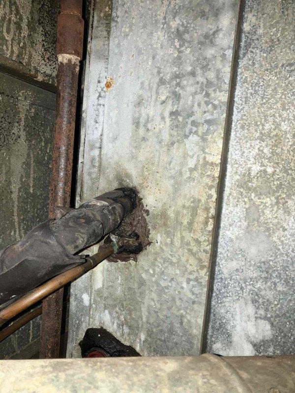Responded to service call for air conditioning system blowing air but not cooling, with indoor temperature reading 77°F. Performed comprehensive system evaluation and diagnostic assessment of existing HVAC equipment. Inspection revealed aging system with deteriorated refrigerant line penetrations through foundation wall, showing significant corrosion on copper piping and compromised wall integrity at pipe entry points. Observed galvanized ductwork with rust staining and signs of long-term moisture exposure in basement mechanical space. System assessment confirmed loss of cooling capacity with airflow present but no temperature reduction. Provided detailed estimate for complete HVAC system replacement due to age and condition of existing equipment, including new air conditioning unit, associated refrigerant lines, and necessary infrastructure upgrades to address deteriorated components and ensure proper system performance.