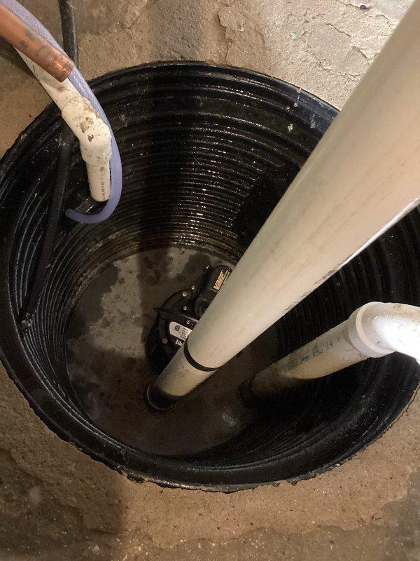 Responded to service call for non-operational sump pump serving basement bathroom with water accumulation on floor. Upon arrival, inspected sump pump basin installation with standing water present and confirmed pump failure with no electrical breaker trip indicated. Diagnosed complete pump malfunction, documented existing installation configuration including PVC discharge piping and electrical junction box setup, and performed necessary repairs to restore proper sump pump operation and drainage functionality.