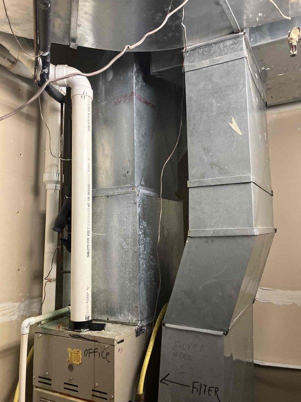 Conducted on-site assessment of two non-operational HVAC systems located at front of building. Evaluated existing equipment including aged furnace unit in basement/utility area with deteriorated ductwork showing significant dust accumulation and surface wear, as well as outdoor condensing unit positioned on concrete pad against exterior brick wall. Documented current system configuration including vertical sheet metal ductwork, PVC condensate piping, electrical disconnect, and cabinet-style furnace with filter access points. Photographed equipment conditions and installation details to develop comprehensive replacement options for complete AC and furnace system upgrades. Provided customer with technical specifications and equipment recommendations for dual system replacement to restore climate control functionality.