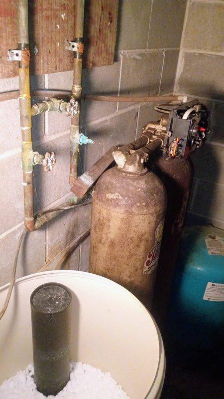 Responded to service call regarding malfunctioning water softener system. Upon arrival, conducted thorough inspection of basement utility area and water treatment equipment. Examined heavily corroded water softener tank showing significant rust accumulation and surface deterioration. Inspected all valve connections, gauges, and plumbing fittings associated with the softener system. Evaluated copper supply lines and distribution piping for proper operation. Assessed pressure tank condition and verified gauge readings. Examined filter cartridge system and noted maintenance requirements. Photographed equipment condition for documentation purposes. Provided customer with diagnostic findings regarding the deteriorated state of the water softener tank and recommended replacement options due to extensive corrosion and age-related wear compromising system integrity and performance.