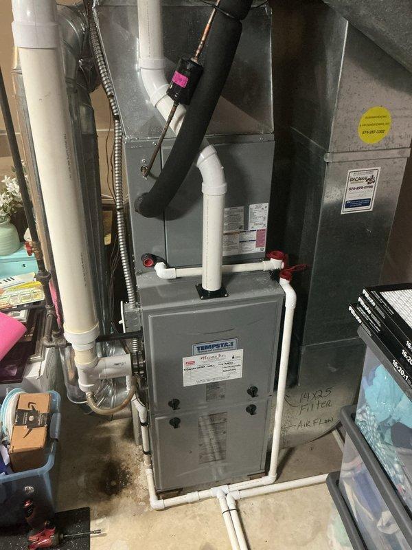 Responded to no cooling complaint on 5-year-old Tempstar system with airflow present but warm air delivery. Performed diagnostic evaluation of residential split system located in basement utility area. Inspected furnace/air handler unit and accessed control board compartment to assess electrical connections and system operation. Verified blower motor function and examined control board wiring, terminals, and safety circuits. Documented system configuration including PVC condensate drainage, air handler components, and ductwork connections for diagnostic purposes.