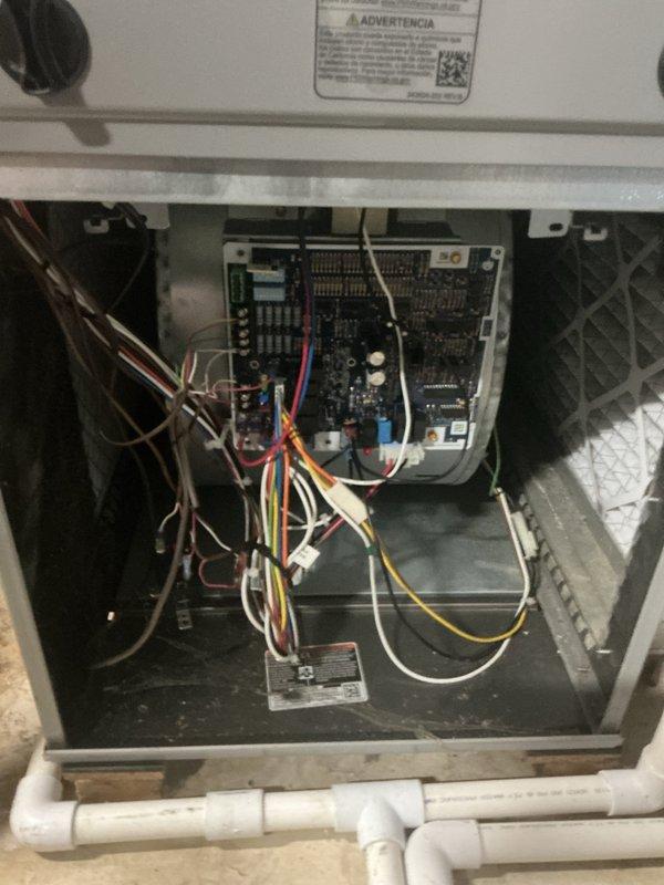 Responded to no cooling complaint on 5-year-old Tempstar system with airflow present but warm air delivery. Performed diagnostic evaluation of residential split system located in basement utility area. Inspected furnace/air handler unit and accessed control board compartment to assess electrical connections and system operation. Verified blower motor function and examined control board wiring, terminals, and safety circuits. Documented system configuration including PVC condensate drainage, air handler components, and ductwork connections for diagnostic purposes.