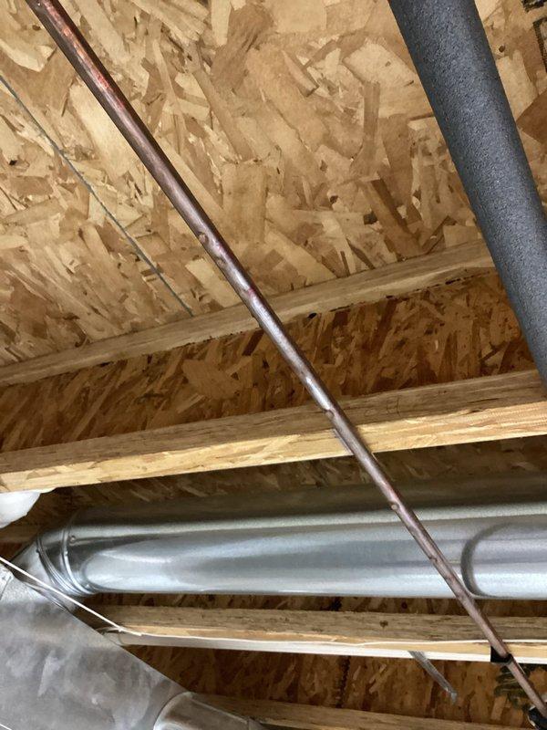 Responded to emergency call for leaky pipe in basement of 25-year-old residential property. Upon arrival, located active leak in copper water line running through unfinished basement ceiling area near HVAC ductwork and structural framing. Leak appeared recent, estimated to have been active for approximately 24 hours based on water accumulation and customer report. Shut off water supply to affected line, assessed damage to copper piping at failed joint connection, and repaired leak using appropriate coupling and soldering techniques. Verified repair integrity through pressure testing and restored water service. Inspected surrounding plumbing infrastructure, including adjacent PVC drain lines and insulated pipes, to ensure no additional leaks or compromised connections were present. Documented conditions with photographs showing exposed utilities, OSB sheathing, wooden framing members, and metallic ductwork in the work area for customer records.