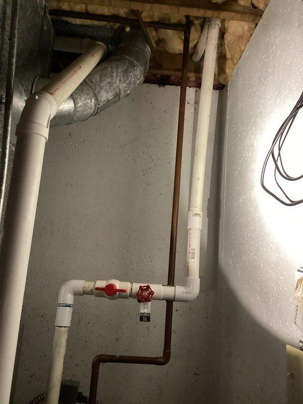 Responded to a follow-up water leak in the basement on the same pipe previously serviced. Upon inspection, identified a new leak located lower down on the copper piping assembly near the water heater system. Assessed the plumbing configuration, which included copper pipe connections, PVC components, gate valves, and an expansion tank. Documented the leak location with photographs showing the affected copper piping, valve assembly, and surrounding plumbing infrastructure for repair recommendations.