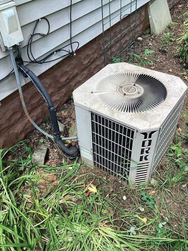 Responded to no cooling complaint following power outage. Found thermostat displaying "cooling is off" with flashing indicator. Reset thermostat to restore cooling mode operation. Inspected 13-year-old York condenser unit located at exterior; observed heavy debris accumulation around base and significant corrosion on contactor assembly. Cleared leaves and organic debris from unit perimeter and interior compartment. Verified capacitor mounting secure and electrical connections intact despite visible oxidation on contactor terminals. Cycled system to confirm proper operation; unit engaged and began cooling cycle successfully. Advised homeowner that heavily corroded contactor and aging system components warrant monitoring and potential replacement to prevent future failure.