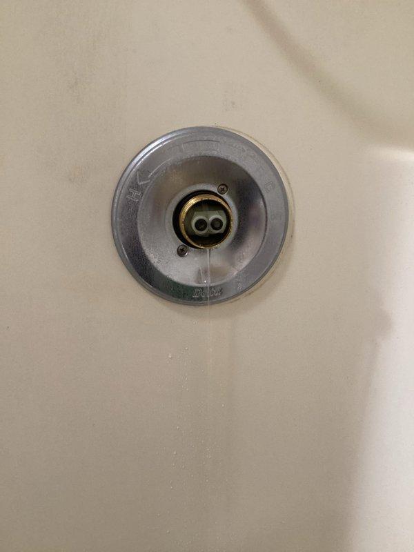Responded to service call for leaking tub faucet that had been dripping for approximately one month in a 24-year-old home. Inspected the bathtub drain assembly and overflow components, documented existing conditions showing visible corrosion, mineral deposits, and age-related deterioration on the metallic fixtures. Photographed the drain cover and overflow plate to record the extent of wear and water damage present on the chrome-plated components.