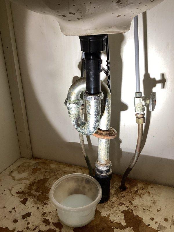 Responded to water leak in master bathroom under sink. Upon inspection, found severely corroded chrome P-trap assembly with rust deterioration on horizontal pipe sections and connection points. Observed extensive water staining on cabinet interior surfaces indicating ongoing moisture intrusion. Replaced failed corroded P-trap assembly with new chrome P-trap, ensuring proper alignment and secure connections at drain tailpiece and waste arm. Tested system for leaks and verified proper drainage function. Advised of existing water damage to cabinet interior from previous leakage.