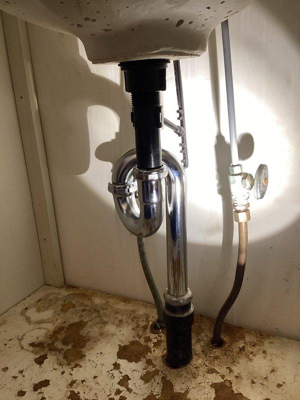 Responded to water leak in master bathroom under sink. Upon inspection, found severely corroded chrome P-trap assembly with rust deterioration on horizontal pipe sections and connection points. Observed extensive water staining on cabinet interior surfaces indicating ongoing moisture intrusion. Replaced failed corroded P-trap assembly with new chrome P-trap, ensuring proper alignment and secure connections at drain tailpiece and waste arm. Tested system for leaks and verified proper drainage function. Advised of existing water damage to cabinet interior from previous leakage.
