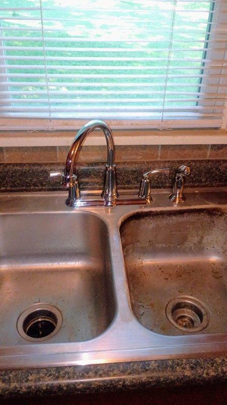 Provided comprehensive estimate for complete kitchen sink replacement in 1940s-era home. Assessed existing stainless steel double-basin sink with malfunctioning faucet, deteriorated basin condition showing significant mineral deposits and staining, and aging disposal unit on left compartment. Documented existing drain assembly including white PVC P-trap configuration, air admittance valve, and braided stainless steel supply lines showing wear and discoloration. Estimate includes removal and replacement of double-compartment sink, faucet assembly with handles and spray attachment, garbage disposal, complete drain piping system including new P-trap, and connection to main kitchen drain line beneath granite countertop.