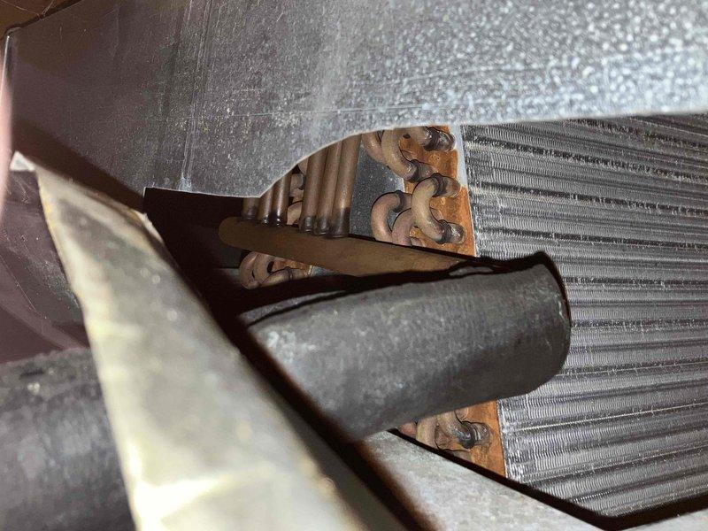 Responded to service call for HVAC system evaluation on residential unit over 20 years old utilizing R22 refrigerant that was found frozen up and inoperable. Conducted comprehensive assessment of existing air conditioning system including inspection of evaporator coil assembly located in attic space and associated ductwork infrastructure. Documentation revealed significant age-related deterioration including visible corrosion and oxidation on copper refrigerant lines, compromised heat exchanger components, and accumulated debris within finned coil sections. System assessment confirmed unit has exceeded serviceable lifespan and utilizes obsolete R22 refrigerant that is no longer readily available or cost-effective for repairs. Captured photographic documentation of existing equipment condition showing deteriorated evaporator coil with rust formation, aging ductwork connections, and overall system infrastructure. Prepared detailed replacement estimate for complete HVAC system upgrade to 