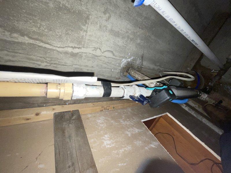 Responded to water leak at main water line entry point into residence. Located active leak on incoming water supply line in crawl space where service enters structure. Installed black rubber repair coupling on white PVC pipe to stop leak and restore water integrity. Secured repair with proper fasteners and verified no additional leaks present at connection points. Water supply restored to normal operation with no standing water remaining in affected area.