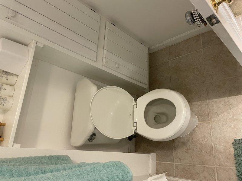 Responded to service call for reported water leak from upstairs toilet running down exterior plumbing lines into basement. Upon arrival, water supply was already shut off by homeowner with no standing water present. Conducted thorough inspection of upstairs bathroom toilet and surrounding plumbing fixtures. Examined toilet base, supply line connections, flush valve assembly, and wax ring seal for signs of active leakage or water damage. Documented bathroom conditions with photographic evidence showing clean, well-maintained fixtures and no visible water staining on flooring or walls at time of inspection.