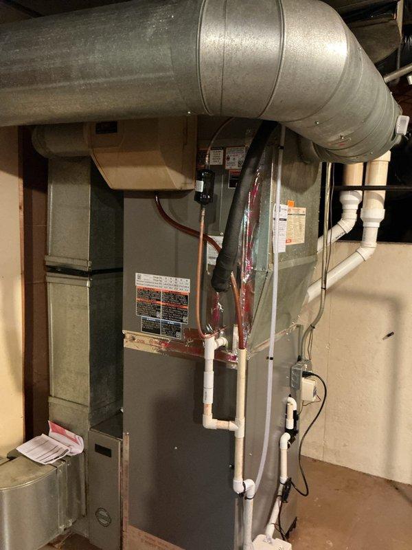 Completed installation of new Lennox ML13KC1-048 air conditioning system with matching CK40CT-49C evaporator coil. Removed existing evaporator coil from plenum to access and inspect the 20-year-old furnace heat exchanger for cracks and structural integrity. Temporarily removed and reinstalled humidifier to facilitate coil access during installation. Extracted coil from cabinet housing and slid into existing plenum, preserving original coil cabinet for future use. Reused existing thermostat to maintain customer's preferred control interface. Installed refrigerant lines connecting outdoor condensing unit to indoor evaporator coil, performed vacuum and pressure testing, and charged system to manufacturer specifications. Verified proper airflow, temperature differential, and system operation upon startup. All connections secured and system left in full operational condition.