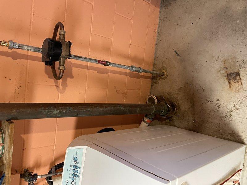 Responded to water leak service call and performed drain cleaning as quoted. Accessed plumbing connections in utility area behind washing machine where water supply lines and shut-off valves are located on tiled wall. Completed drain cleaning procedure to resolve drainage issue and restore proper water flow. Documented pre-existing conditions including water staining on adjacent concrete surfaces and verified all plumbing connections secure upon completion.