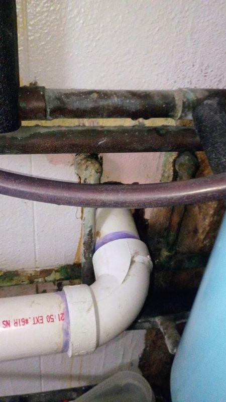 Provided plumbing components for under-sink installation including white PVC P-trap assembly with threaded fittings and braided stainless steel supply lines with shutoff valves. Customer purchased materials to replace heavily corroded metal drain pipes and deteriorated fixtures showing extensive rust and oxidation damage beneath existing sink.