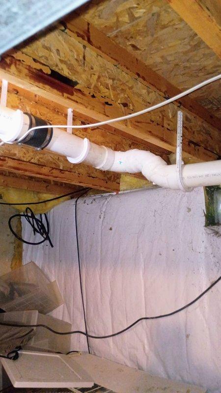 Completed repipe of drain line section in basement crawl space to correct back-sloping condition that was causing improper drainage. Removed existing improperly pitched PVC drain piping and installed new properly sloped drain line with appropriate hangers and support brackets secured to floor joists. The new installation ensures proper gravity flow and eliminates potential for standing water or backflow issues in the drainage system.