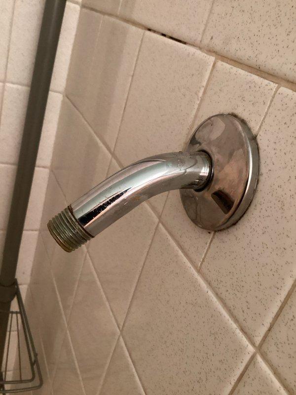 Responded to service call for stuck showerhead that had been installed for over 20 years. Successfully removed the old showerhead from the chrome shower arm extending from the tiled bathroom wall. Replaced with new showerhead assembly including inline water filtration component with brass body and chrome fittings. Verified proper threading connection and tested for leaks. System operating properly upon completion.