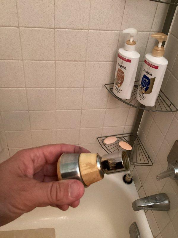 Responded to service call for stuck showerhead that had been installed for over 20 years. Successfully removed the old showerhead from the chrome shower arm extending from the tiled bathroom wall. Replaced with new showerhead assembly including inline water filtration component with brass body and chrome fittings. Verified proper threading connection and tested for leaks. System operating properly upon completion.