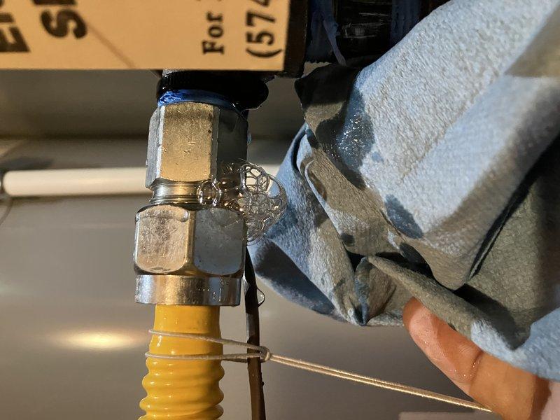 Responded to reported gas leak at furnace connection point. Upon arrival, gas was already shut off at the meter and leak location had been marked by gas company. Performed inspection of flexible gas line connection to furnace, identifying leak at brass fitting connection point. Tightened compression fitting on yellow corrugated flexible gas connector using appropriate wrench while wearing proper safety equipment. Applied thread sealant to ensure proper seal at connection points. Conducted pressure test on gas line to verify leak was resolved and system integrity was restored. All connections tested and confirmed leak-free before restoring gas service.