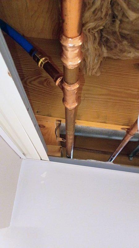 Installed new water supply line from basement to refrigerator location. Ran copper piping through ceiling joists and wall cavity, terminating with a blue-handled ball valve shutoff featuring 1/4" compression fitting at the point of connection. Applied thread sealant at all connection points to ensure leak-free operation and mounted shutoff valve securely to baseboard for easy access.