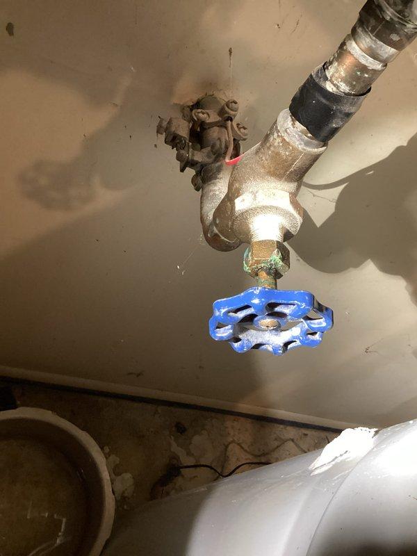 Responded to customer report of sill faucet that would not shut off. Upon inspection, identified exterior hose bib with worn internal components preventing complete water shutoff. Documented existing plumbing configuration including interior shutoff valve with blue handle and brass elbow fittings mounted to ceiling structure. Photographed outdoor spigot installation showing aged fixture with corrosion on body and handle mechanism. Provided customer with counter sale parts and technical guidance for repair, including replacement washer, stem assembly, and installation instructions for restoring proper shutoff function to the exterior faucet.