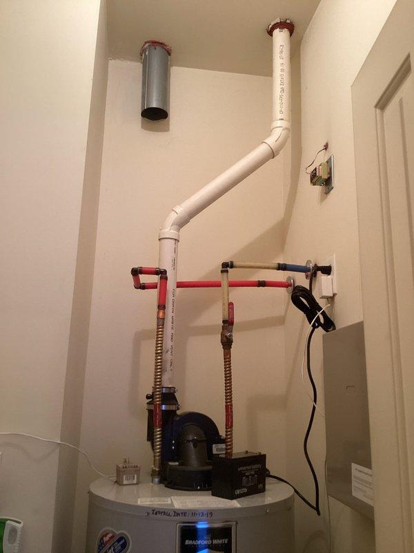 Responded to service call for reported leak on 7-year-old Bradford White tanked water heater. Upon inspection, identified minor water leak at connection point. Unit was operational at time of arrival with digital display functioning normally. Examined all visible plumbing connections, pressure relief valve, inlet/outlet piping, and recirculation pump assembly mounted on top of tank. Documented existing installation configuration including PVC venting system, flexible water lines with red connectors, and electrical connections. Photographed water heater system and surrounding mechanical room conditions for service records.