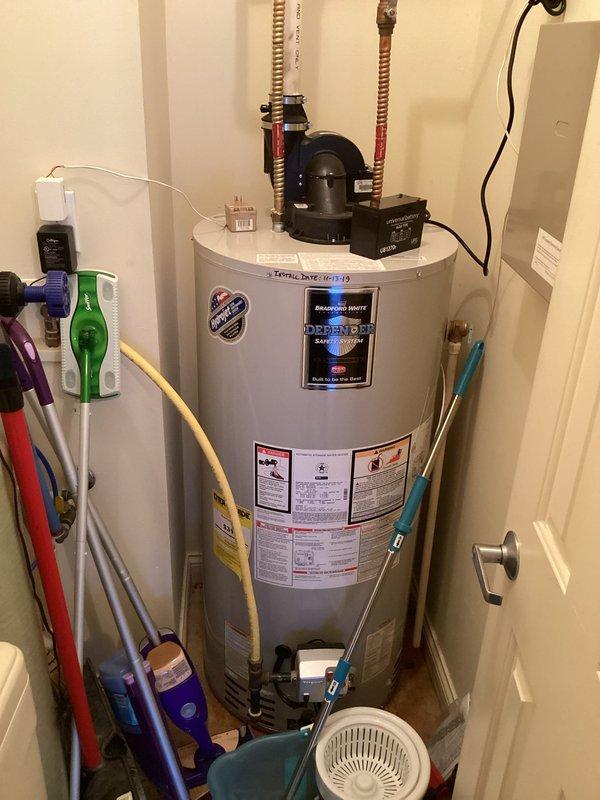 Responded to service call for reported leak on 7-year-old Bradford White tanked water heater. Upon inspection, identified minor water leak at connection point. Unit was operational at time of arrival with digital display functioning normally. Examined all visible plumbing connections, pressure relief valve, inlet/outlet piping, and recirculation pump assembly mounted on top of tank. Documented existing installation configuration including PVC venting system, flexible water lines with red connectors, and electrical connections. Photographed water heater system and surrounding mechanical room conditions for service records.