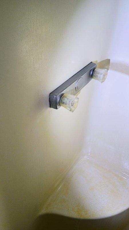 Responded to service call for non-functioning tub spout on wall-mounted chrome faucet assembly. Upon inspection, identified inoperative spout with visible signs of deterioration along tub-to-wall junction including rust staining, mineral deposits, and compromised caulking. Performed diagnostic assessment of three-piece tub faucet system including handles, spout, and overflow assembly. Addressed water flow issues and cleaned affected areas to restore proper functionality. Documented existing conditions including surface staining on tub, discolored grout lines, and aging caulk requiring future maintenance attention.