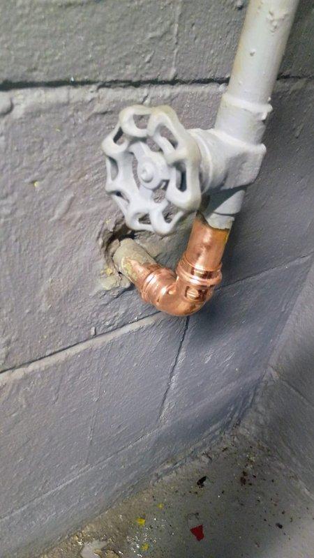 Responded to water leak at main water line entry point where copper elbow fitting had developed a small pinhole leak. Water supply to house was shut off upon arrival. Removed and replaced the deteriorated copper elbow fitting at the connection point where the main line enters the structure from the street. Restored water service and tested system for proper operation and verified no additional leaks at the repair site.