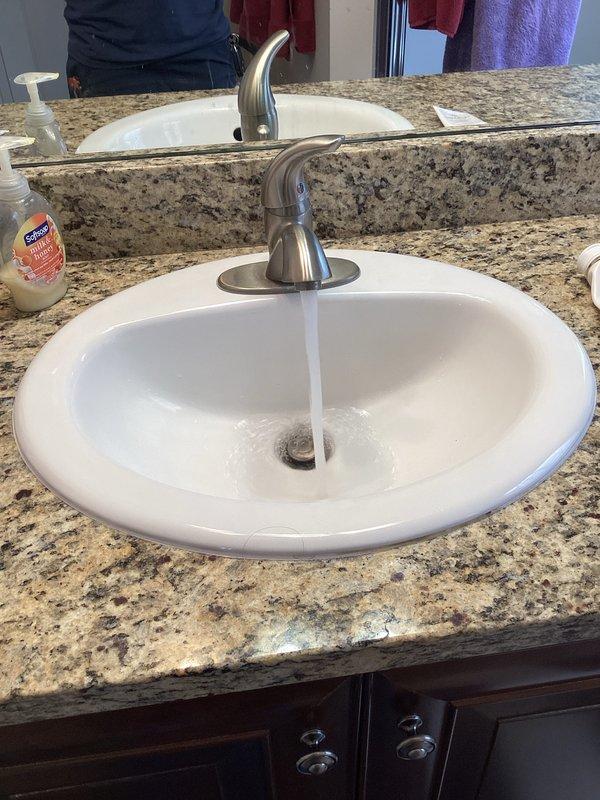 Responded to callback regarding decreased water pressure and extended temperature rise time at upstairs fixtures following recent water heater installation. Performed diagnostic testing at upstairs bathroom faucet to assess flow rate and temperature delivery. Verified proper water flow through single-handle faucet at vanity sink and documented baseline conditions with photographic evidence for service records.