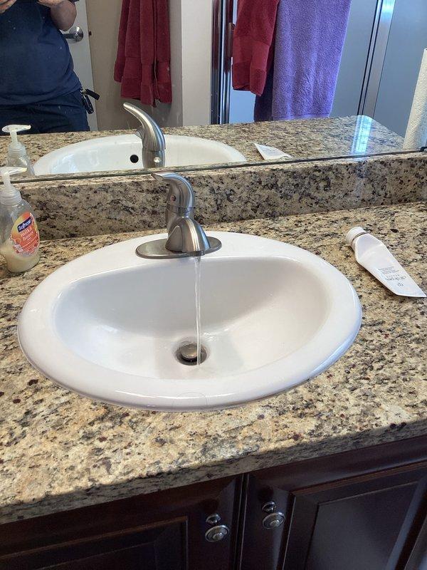 Responded to callback regarding decreased water pressure and extended temperature rise time at upstairs fixtures following recent water heater installation. Performed diagnostic testing at upstairs bathroom faucet to assess flow rate and temperature delivery. Verified proper water flow through single-handle faucet at vanity sink and documented baseline conditions with photographic evidence for service records.