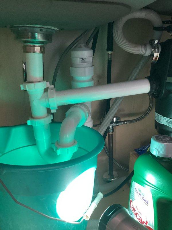 Responded to kitchen water leak caused by disconnected pipes beneath the sink. Upon arrival, inspected the under-sink plumbing configuration which included white PVC P-trap assembly, chrome tailpiece, garbage disposal unit with flexible gray corrugated drain hoses, and associated drain connections. Reconnected and secured the disconnected drain pipes, tightened all slip-joint connections on the P-trap assembly, and verified proper alignment of the garbage disposal discharge line. Tested all connections for leaks by running water through the system and confirmed proper drainage with no active leaks present upon completion.